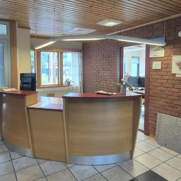 Bilde av serviceskaranken på kommunehuset. En blomst står på skranken. Lamper som henger over. Rød tegelstensvegg i bakgrunnen